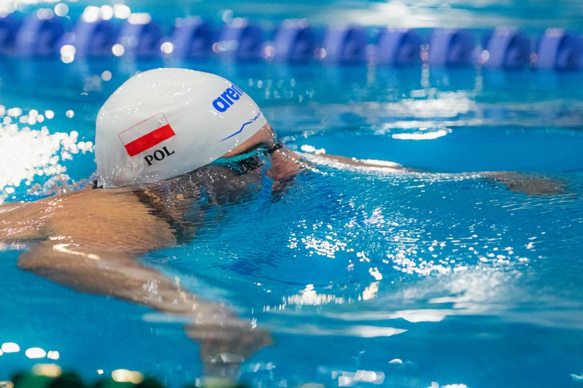 Pływak w białym czepku z polską flagą przy linie torowej. PGE Grand Prix Puchar Polski, Oświęcim, 13.03.2026.